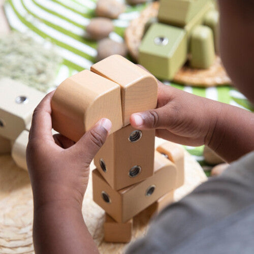 Kinderhanden bouwen een Guidecraft houten giraf van bouwblokken.