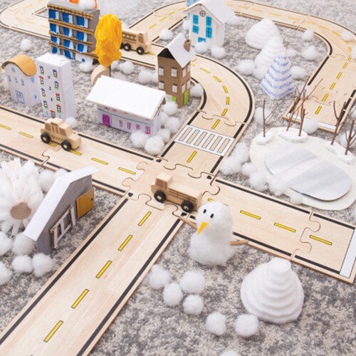 Een houten autoweg opstelling in een winterthema met sneeuwpoppen, huisjes en besneeuwde bomen.
