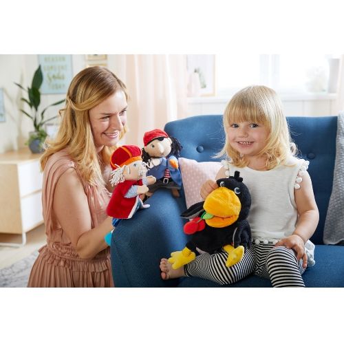 Een kind en een volwassene spelen op een bank met Haba handpoppen, waaronder de raaf, een koning en een piraat.
