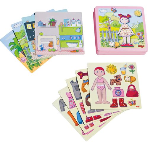 Haba magneetspel aankleedpop Lilli met een roze doos, een pop, diverse kledingstukken en accessoires, en achtergrondkaarten.
