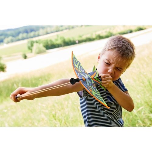 Een jongen spant het Haba Terra Kids katapultvliegtuigje met de elastiek om het te lanceren.
