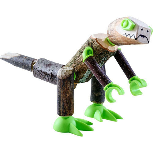 Een knutselset dinosaurus, lijkend op een T-Rex, gemaakt van takken en groene connectors met een getekend gezicht.