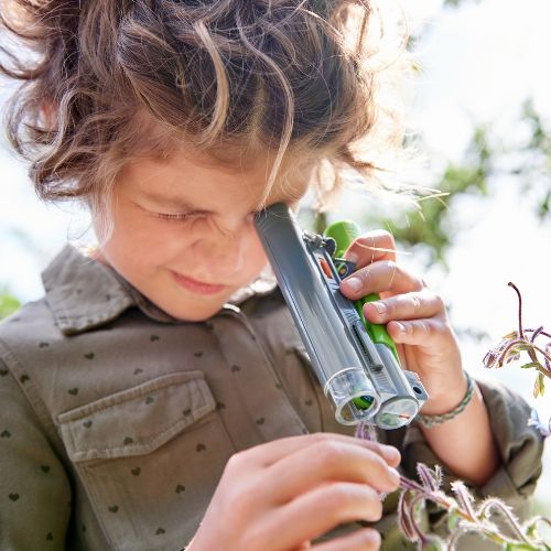 Een kind bekijkt een plant met de Haba Terra Kids veldmicroscoop.