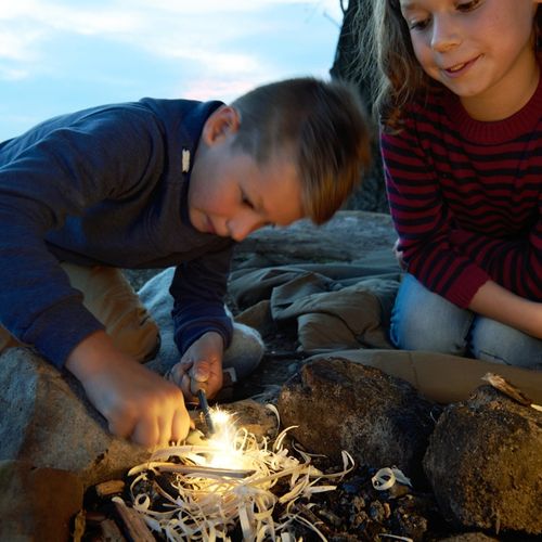 Twee kinderen gebruiken de Haba Terra Kids vuurstarter om een kampvuur aan te steken.