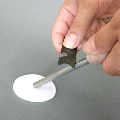 Detailfoto van een hand die de Haba Terra Kids vuurstarter gebruikt om vonken te maken op een katoenen pad.