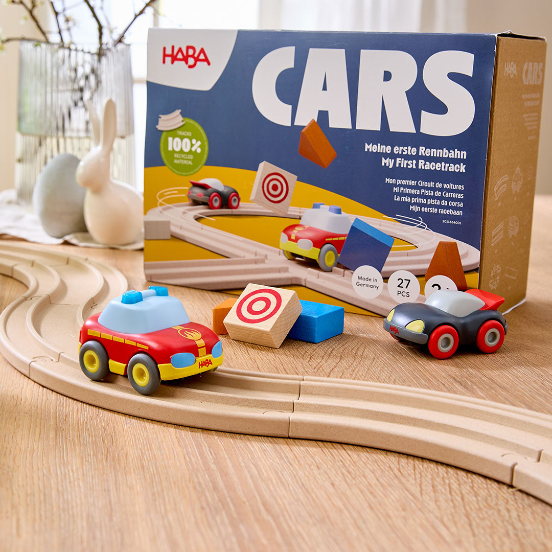 De Haba Cars speelgoedracebaan met twee auto's en houten blokken op een tafel, met de productverpakking op de achtergrond.