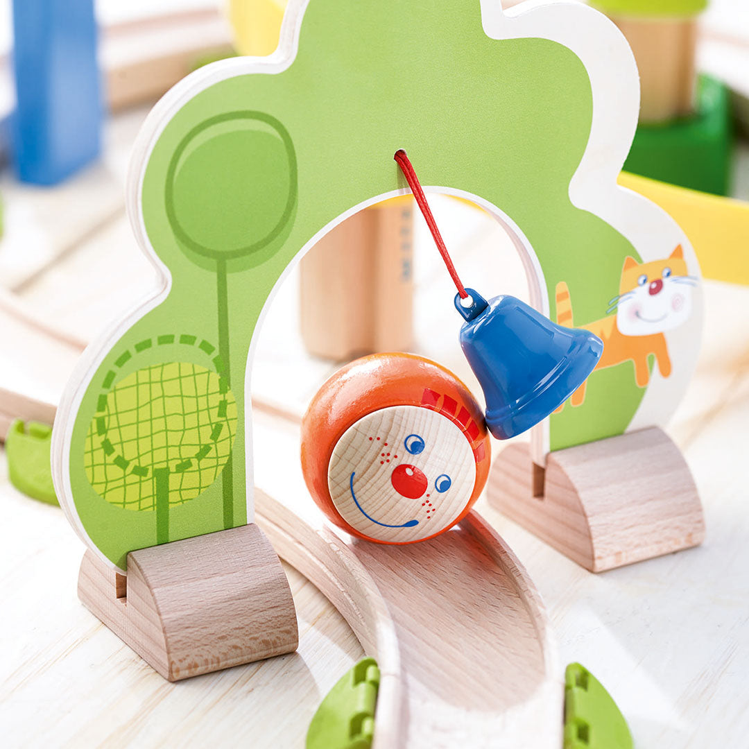 Detail van de HABA Kullerbü knikkerbaan met een bal met clowngezicht die langs de bel rolt.