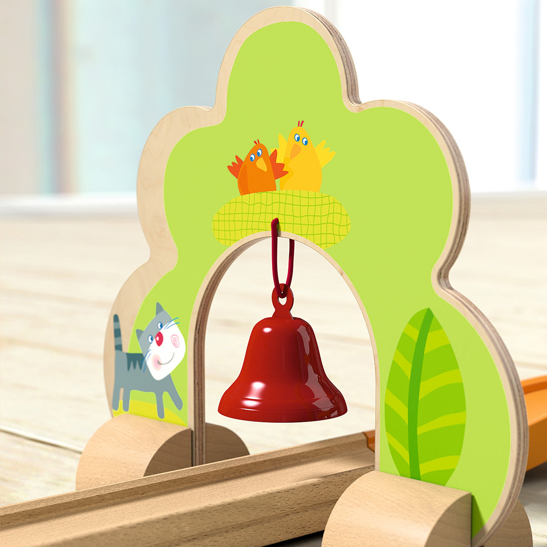 Detail van de HABA Kullerbü knikkerbaan met een houten boog met figuren en een rode bel.