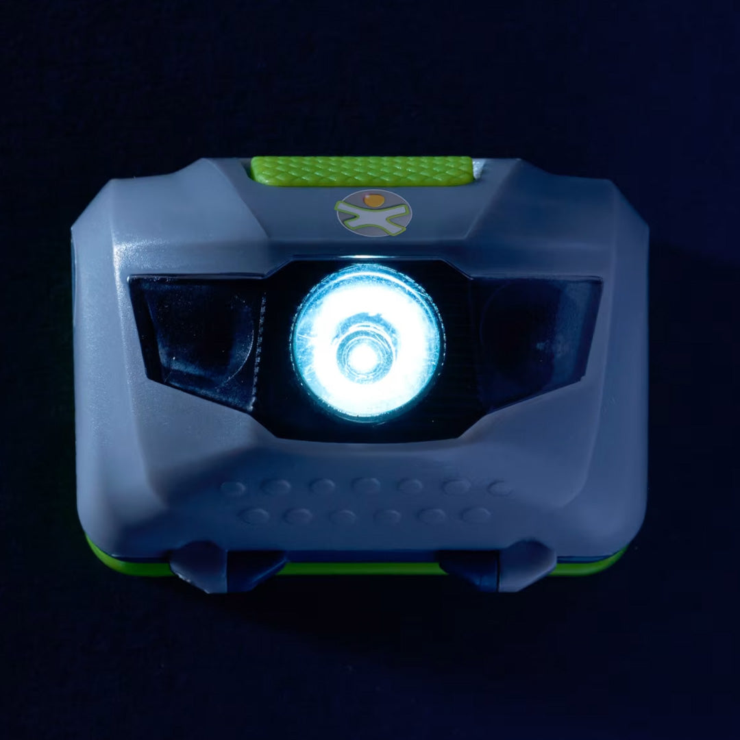 Detailopname van de Haba Terra Kids hoofdlamp met het brandende witte led-licht in het donker.