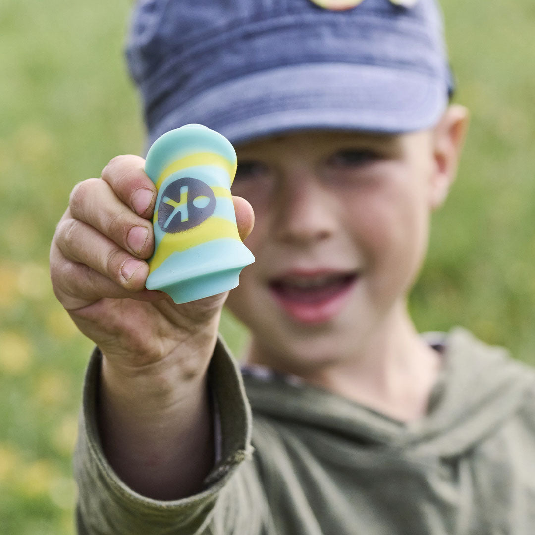 Een jongen houdt een opgevouwen Haba Terra Kids gestreepte mini frisbee van siliconen in zijn hand.
