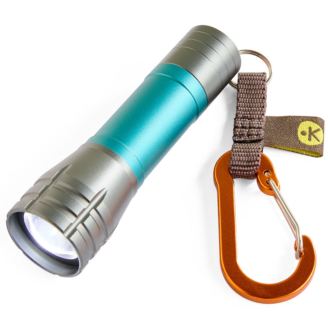 Een schuine close-up van de haba Terra Kids mini zaklamp in grijs en teal met een oranje karabijnhaak.