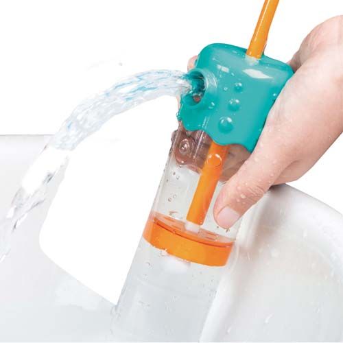 Een hand demonstreert de Hape waterspuit die water spuit in een witte wasbak.