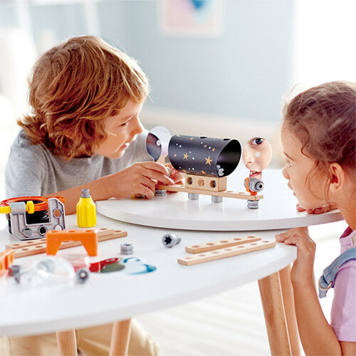 Twee kinderen spelen met de Hape bouwset optica laboratorium op een witte tafel.