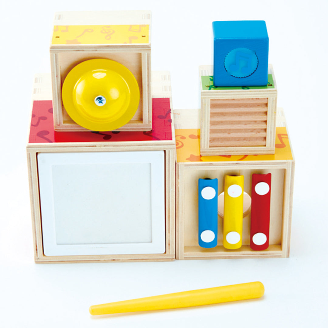 Hape muzikale bouwblokken voor baby's, bestaande uit vijf houten blokken met verschillende instrumenten en een gele drumstick.