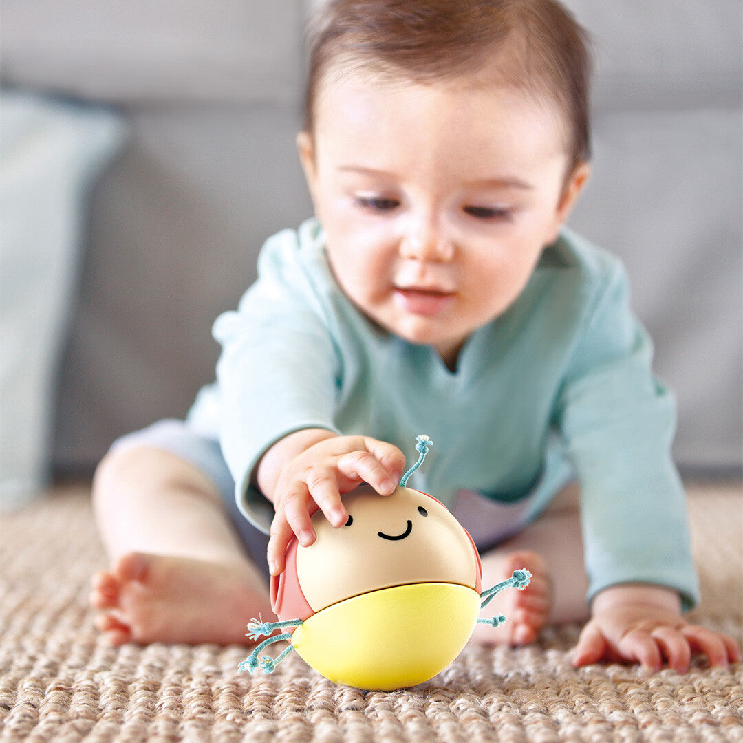 Een baby speelt op een kleed met de Hape rammelaar lieveheersbeestje.