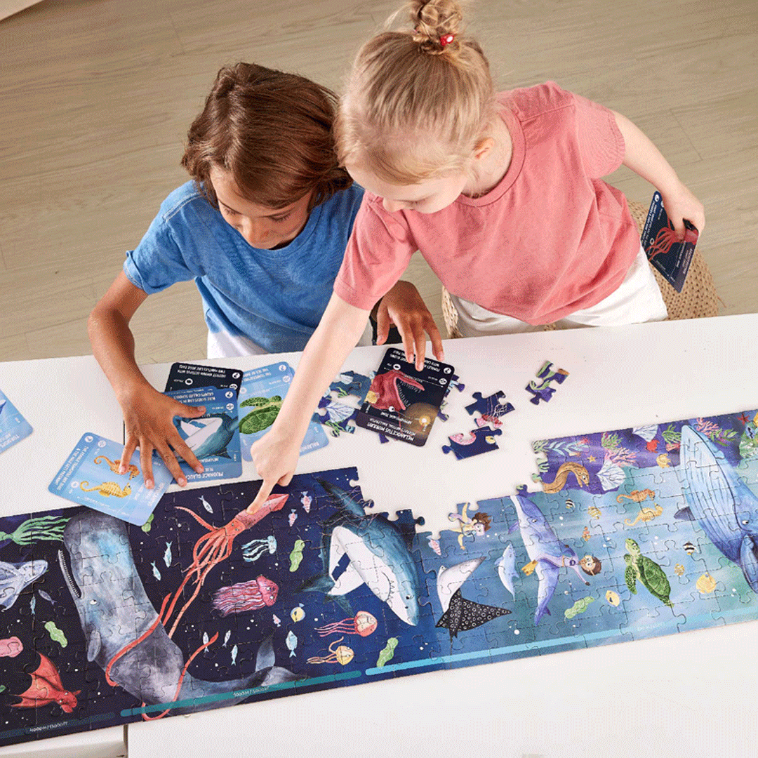 Twee kinderen leggen de Hape oceaan vloerpuzzel met zeedieren en bekijken de informatiekaarten.