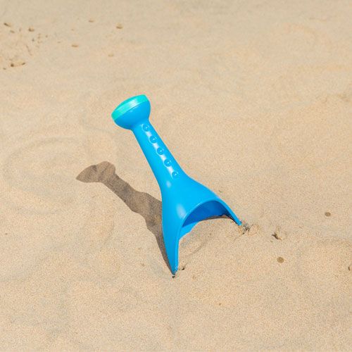Hape blauwe zand en water schep rechtop in het zand.