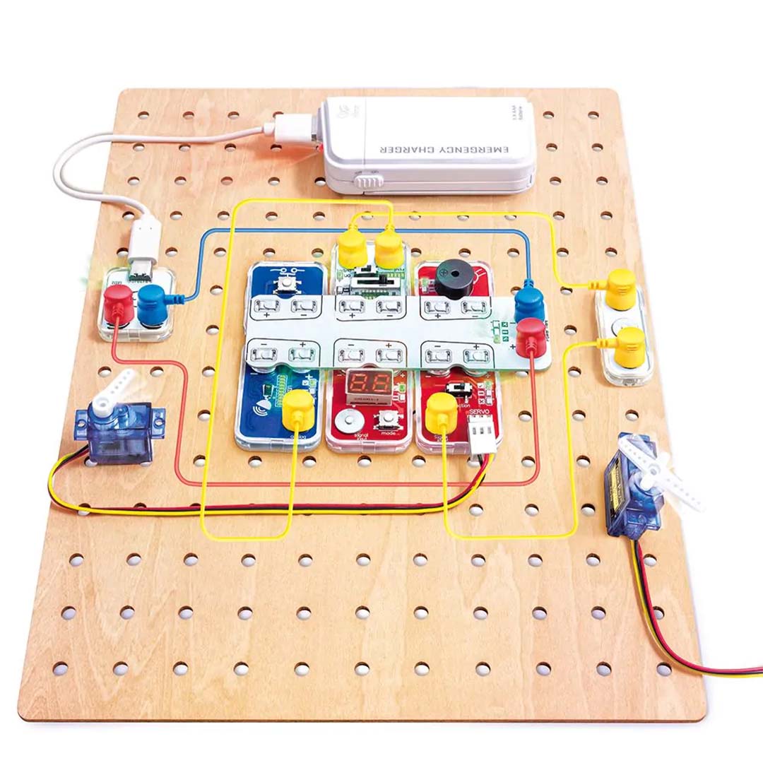 Bovenaanzicht van de Hape Lab Box Circuit Explorer Pro met aangesloten modules op een houten bord.
