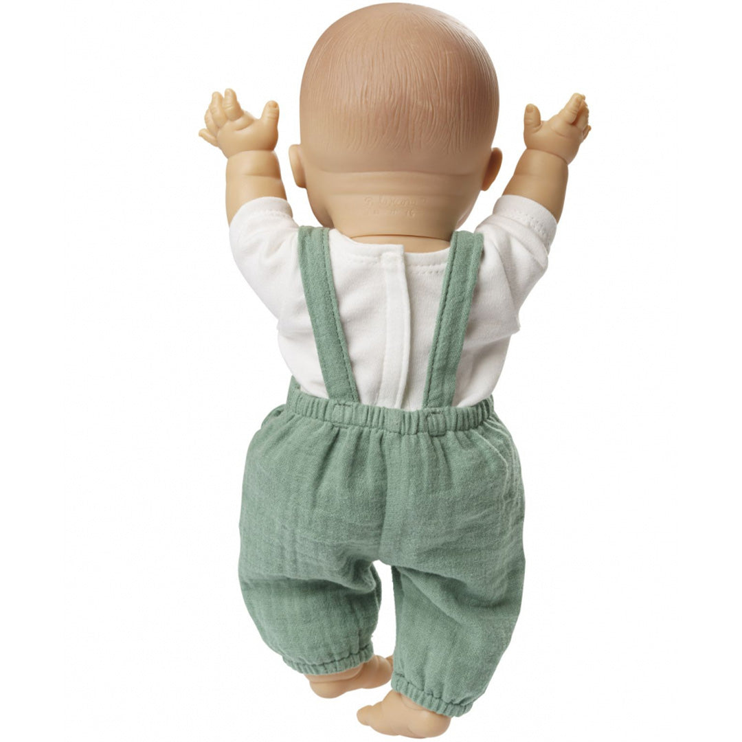 De achterkant van een baby pop die de saliegroene tuinbroek en het witte t-shirt draagt.
