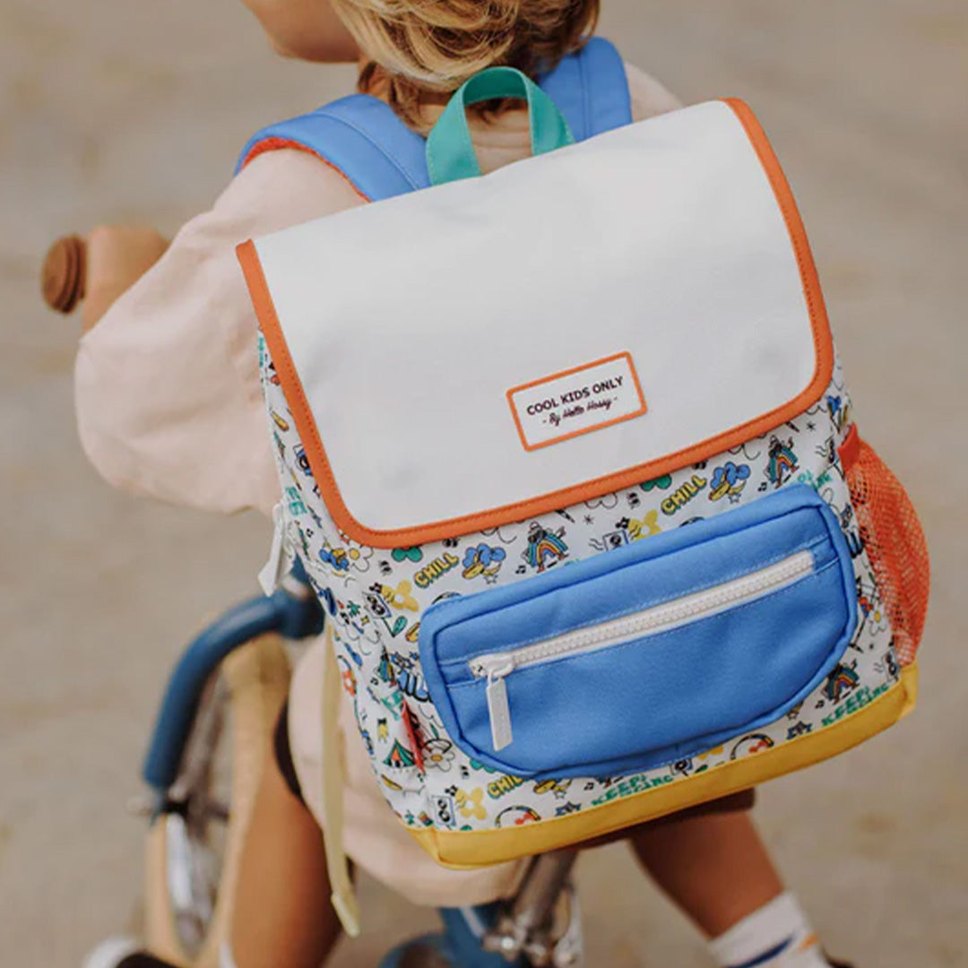 Kind draagt de veelkleurige schoolrugzak met 'Chill' patroon op de rug, zittend op een fiets.