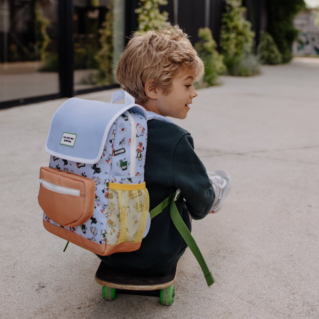 Kind met de hello hossy schoolrugzak met 'dunk' patroon op de rug, zittend op een skateboard.