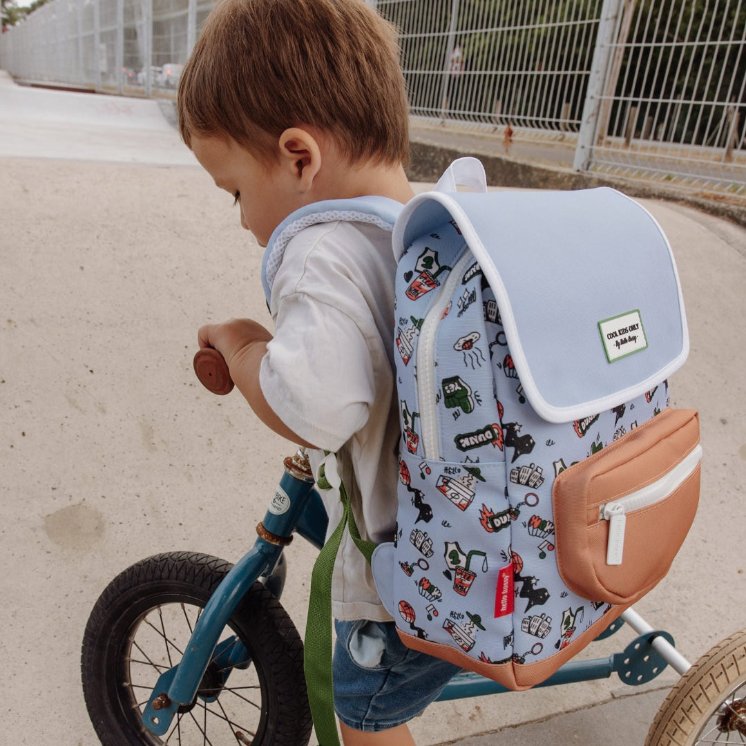 Peuter met de hello hossy schoolrugzak met 'dunk' patroon op de rug, lopend met een loopfiets.