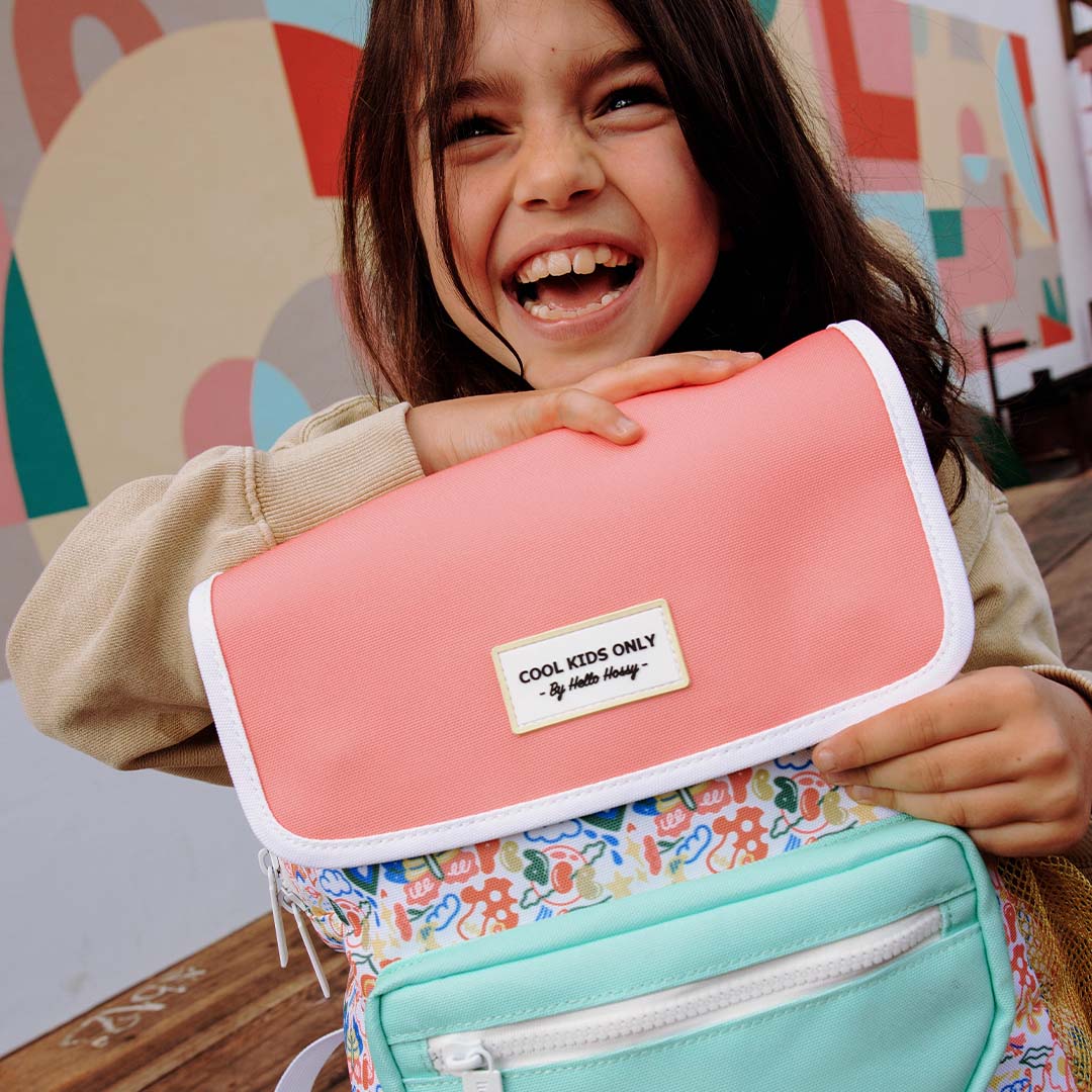Een lachend kind houdt de roze flap van de hello hossy schoolrugzak Happiness vast, met het label 'COOL KIDS ONLY'.