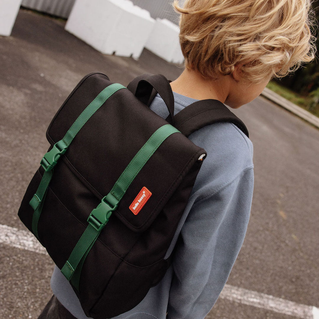 Kind draagt de Hello Hossy schoolrugzak in zwart met groene banden op de rug.