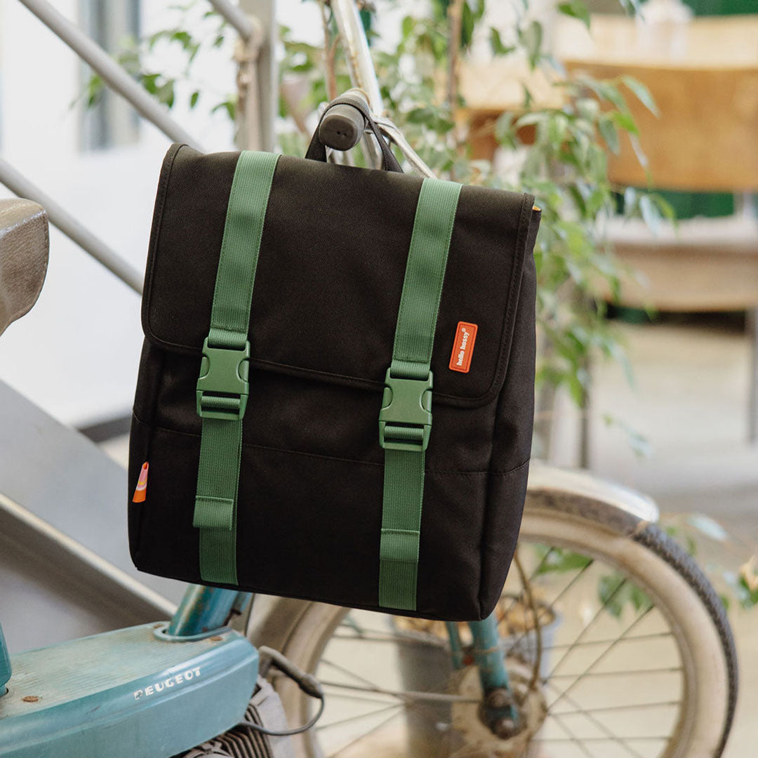 Hello Hossy schoolrugzak in zwart met groene banden hangt aan het stuur van een fiets.