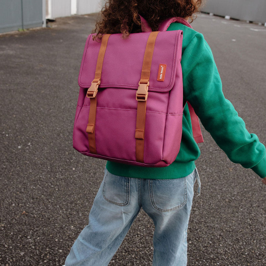Kind draagt de hello hossy schoolrugzak in zinnia paars op de rug, buiten.