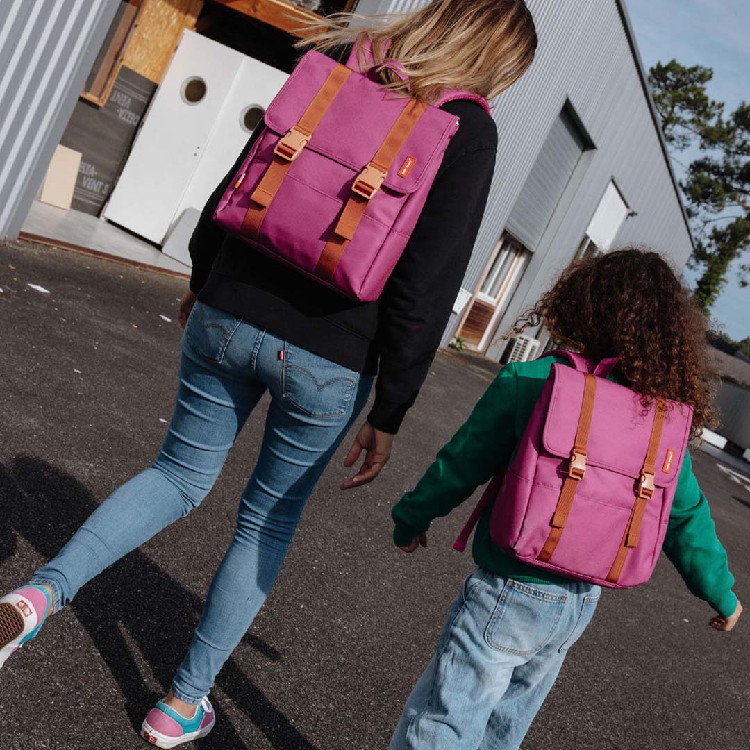 Een volwassene en kind lopen met de hello hossy schoolrugzak in zinnia paars op de rug.