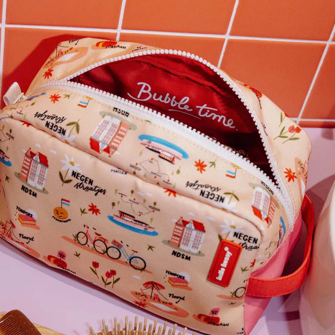 De open Hello Hossy toilettas met Amsterdam-thema toont de rode binnenkant met "Bubble time" tekst, liggend op een badkamerplank.