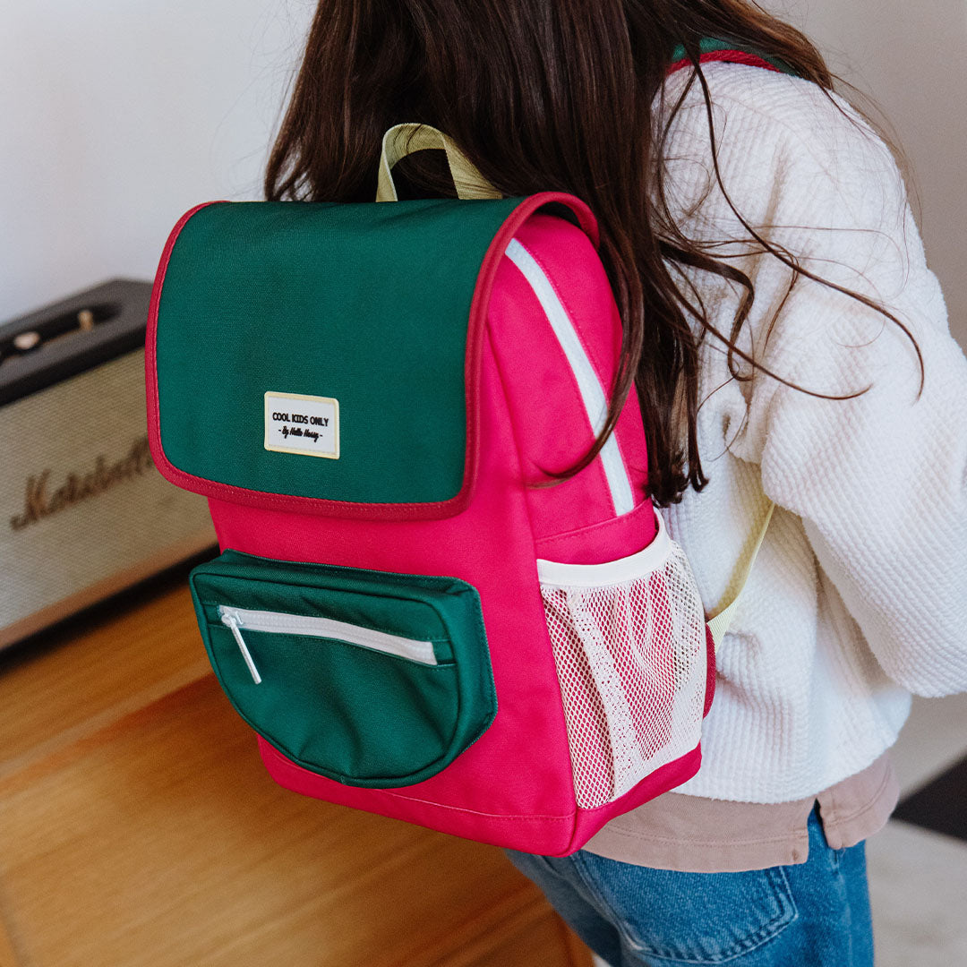 hello hossy kleuterrugzak in roze en groen op de rug van een kind, gezien vanaf de zijkant.