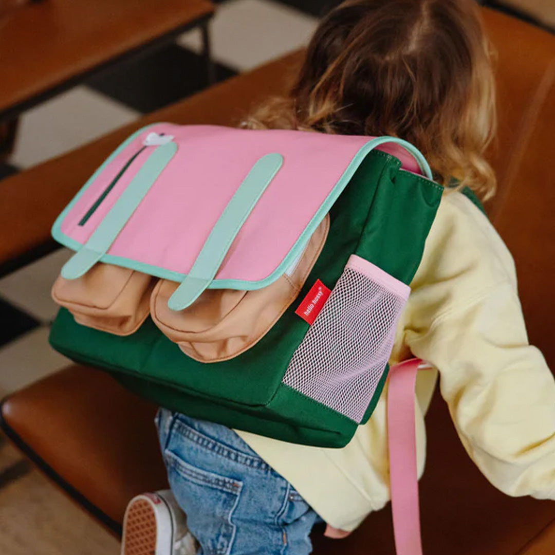 Kind draagt de Hello Hossy schooltas in roze, groen en beige op de rug.