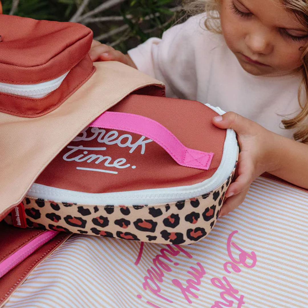Een kind stopt de Hello Hossy lunchtas met luipaardprint in een rugzak.
