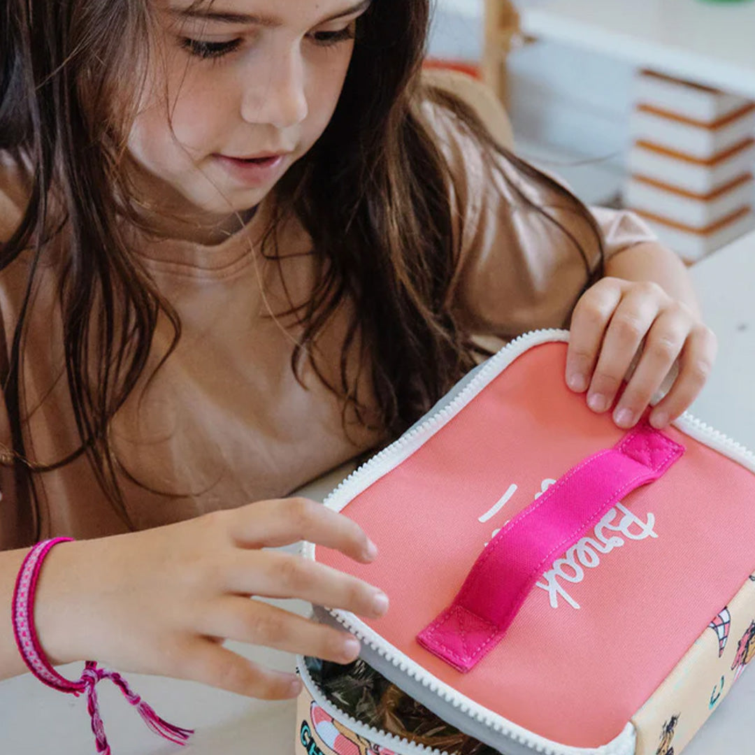 Een kind opent de Hello Hossy snacktas met eenhoornpatroon op een tafel.