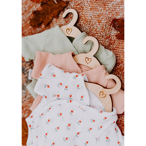 Collectie Hollie poppenkleding rompers in verschillende kleuren op houten hangers.