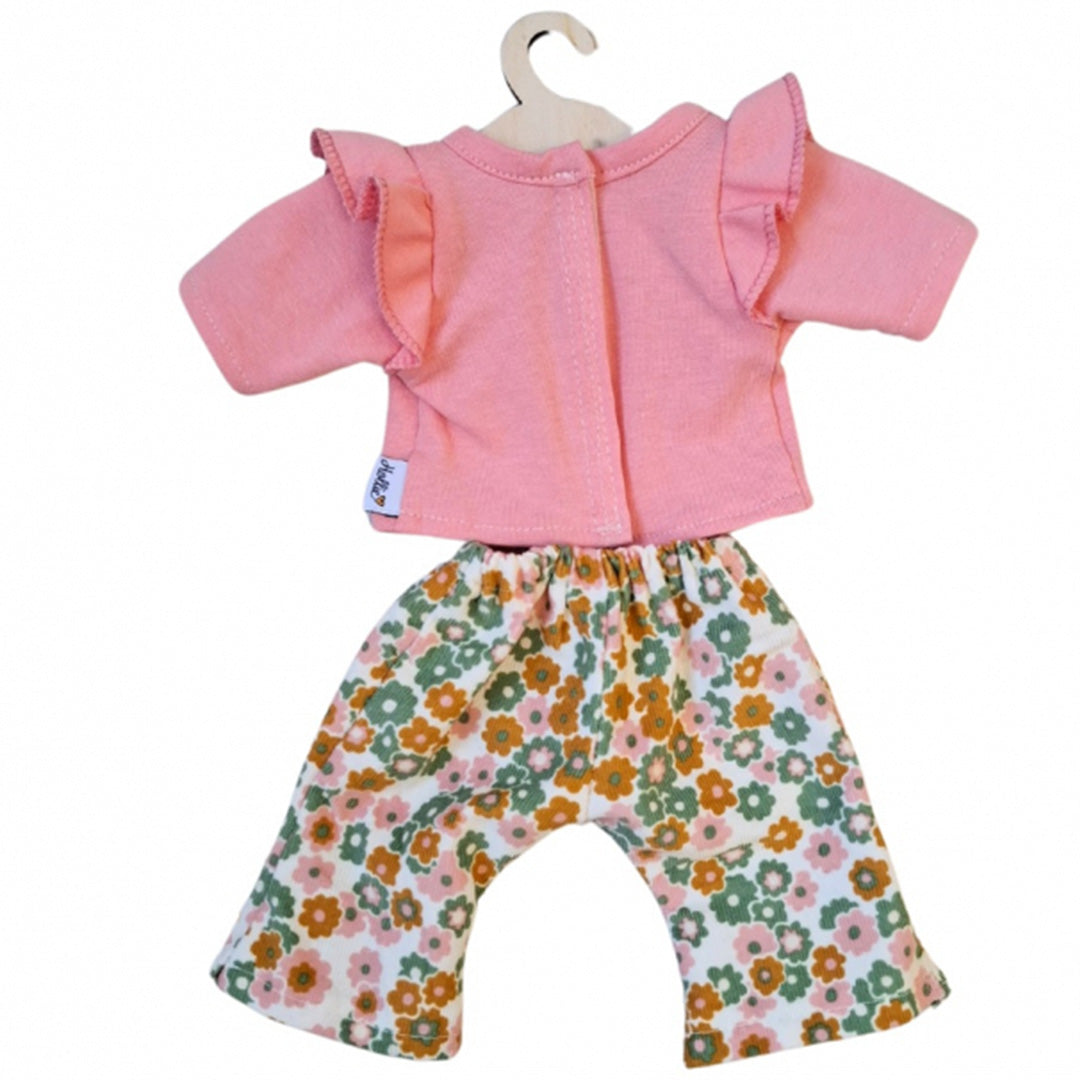 hollie poppenkleding set met een roze shirt met ruches en een gebloemde broek, hangend aan een houten hanger.