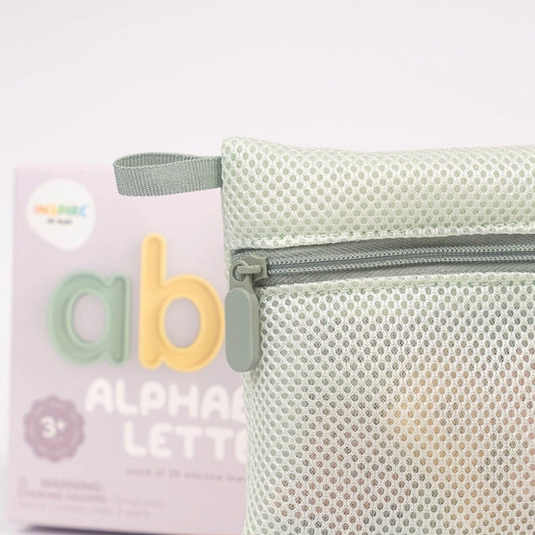 Een lichtgroen gaas zakje met rits, met op de achtergrond de verpakking van de inspire my play alfabet letters.
