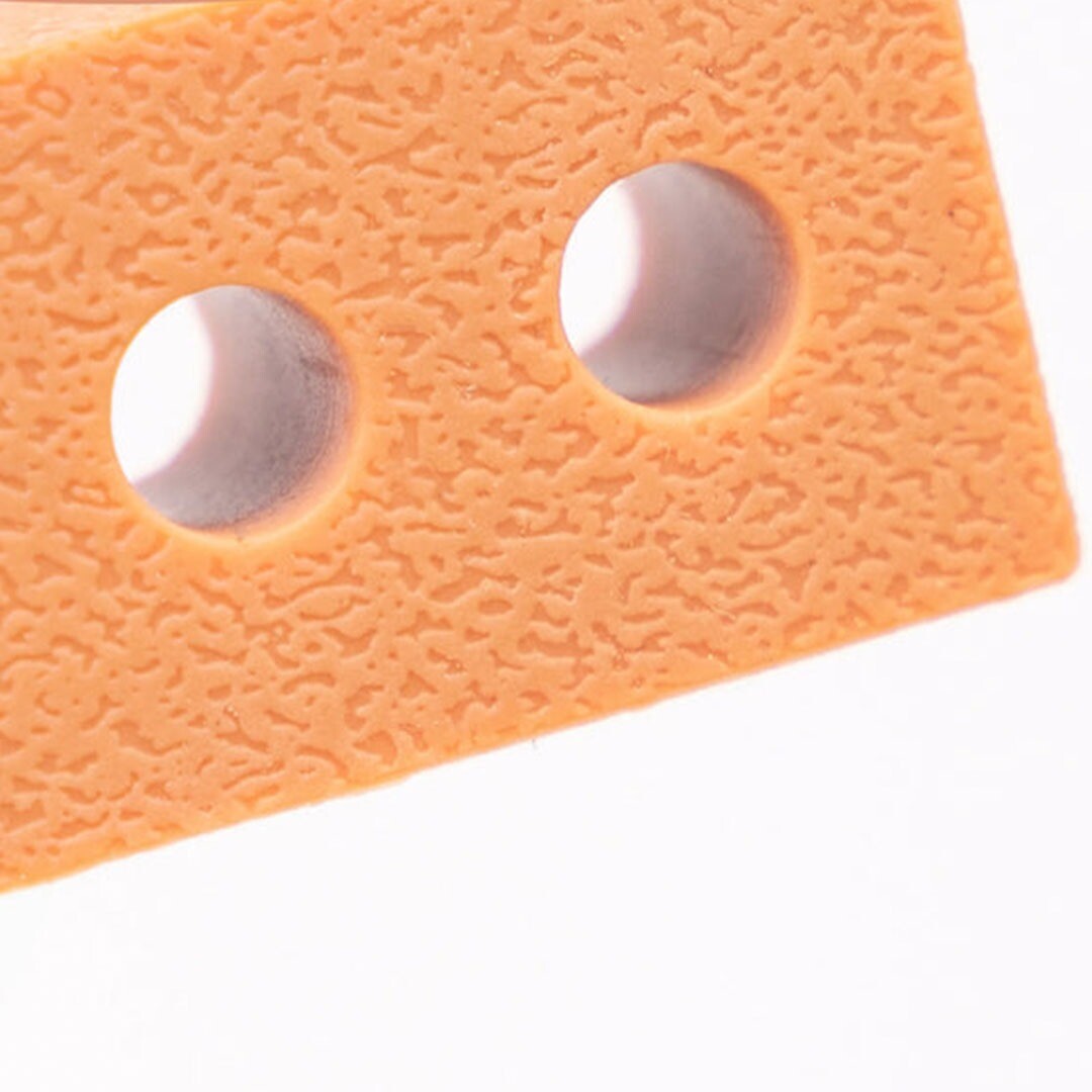 Close-up van de textuur en twee ronde gaten in een oranje Inspire My Play mini brick van siliconen.