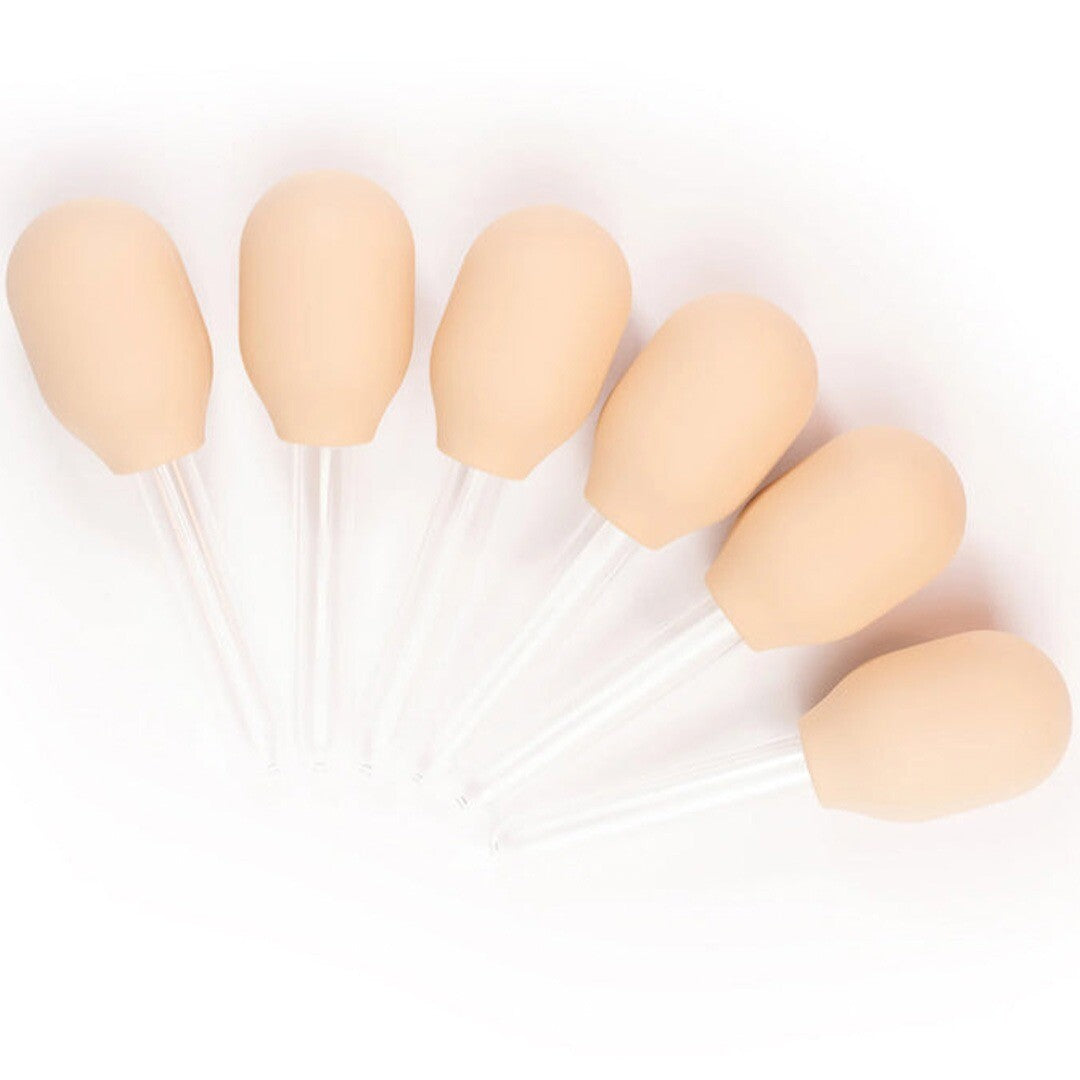 Zes inspire my play beige pipetten voor sensorisch speelgoed liggen schuin op een witte achtergrond.