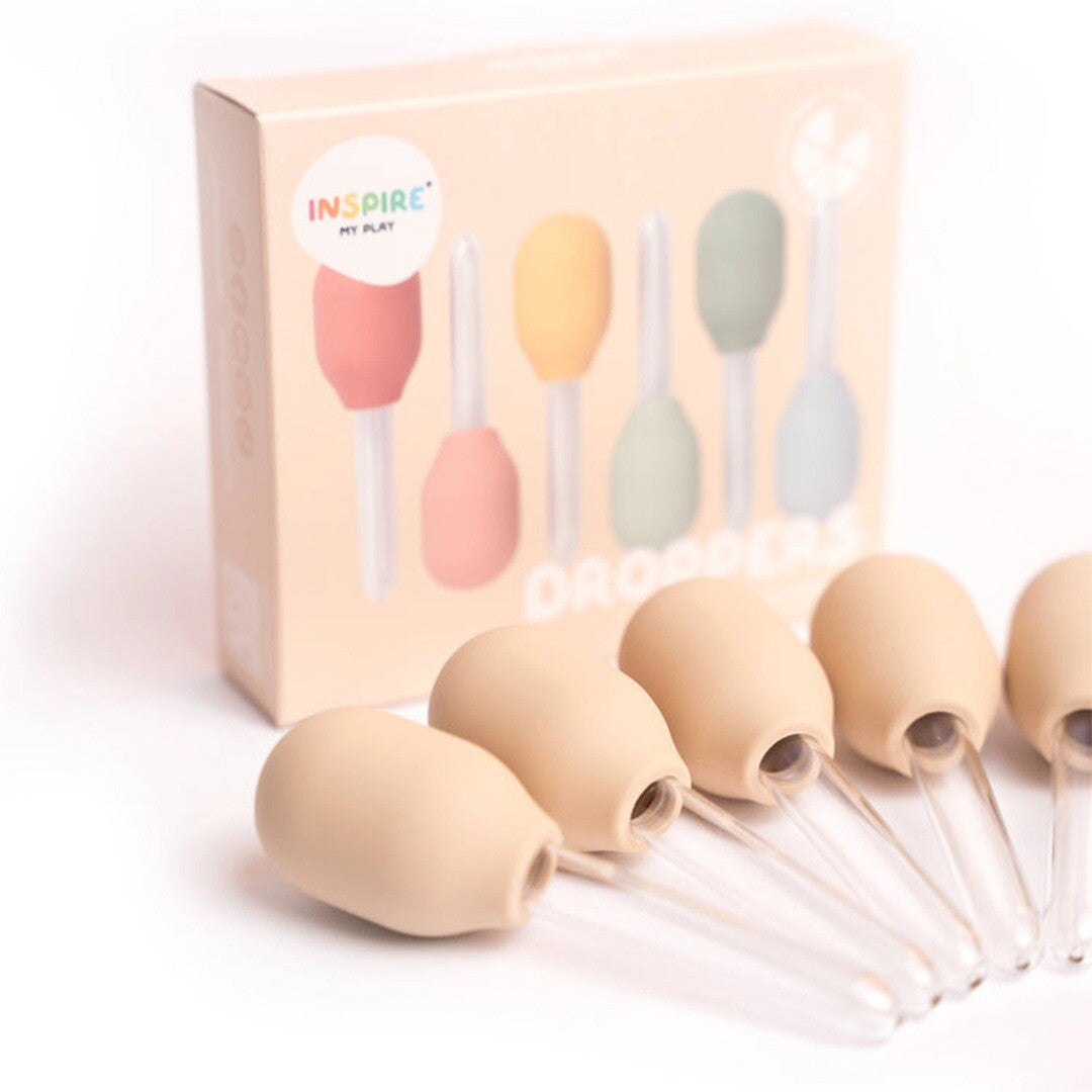 De verpakking van inspire my play droppers staat achter vijf beige pipetten.