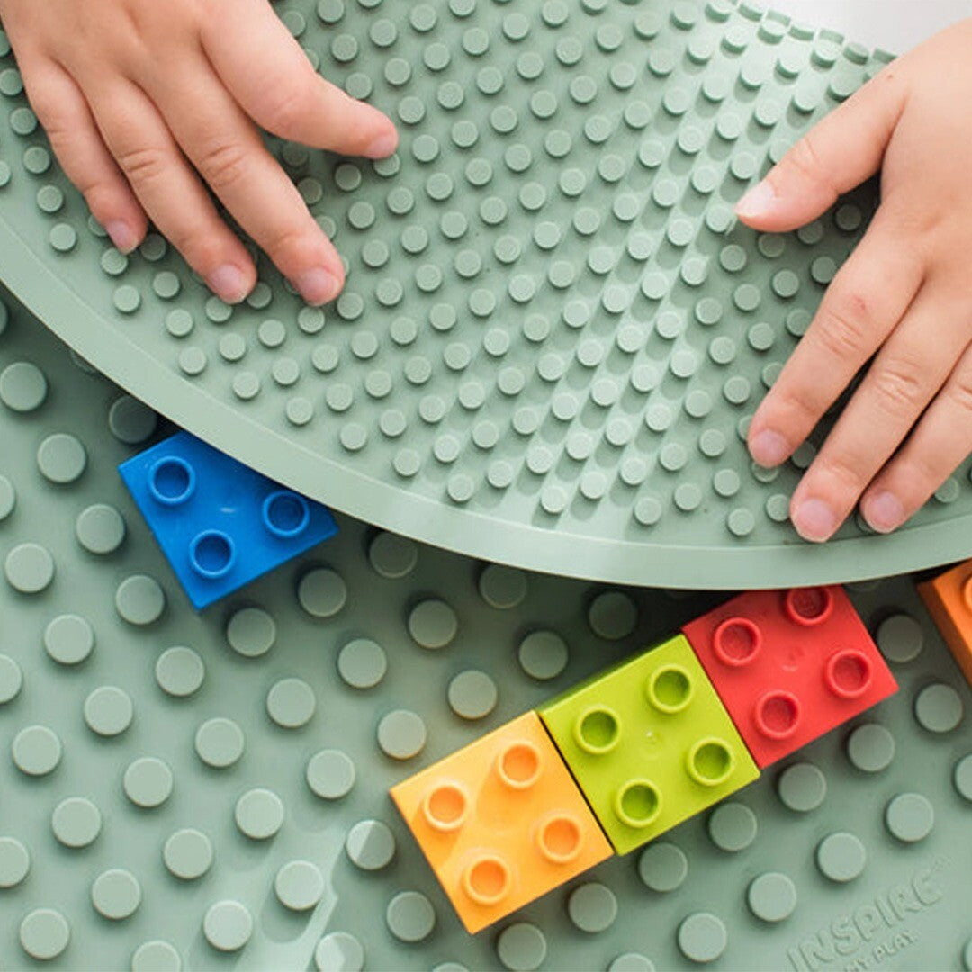 Kinderhanden spelen met kleurrijke bouwblokken op de inspire my play groene bouwmat.
