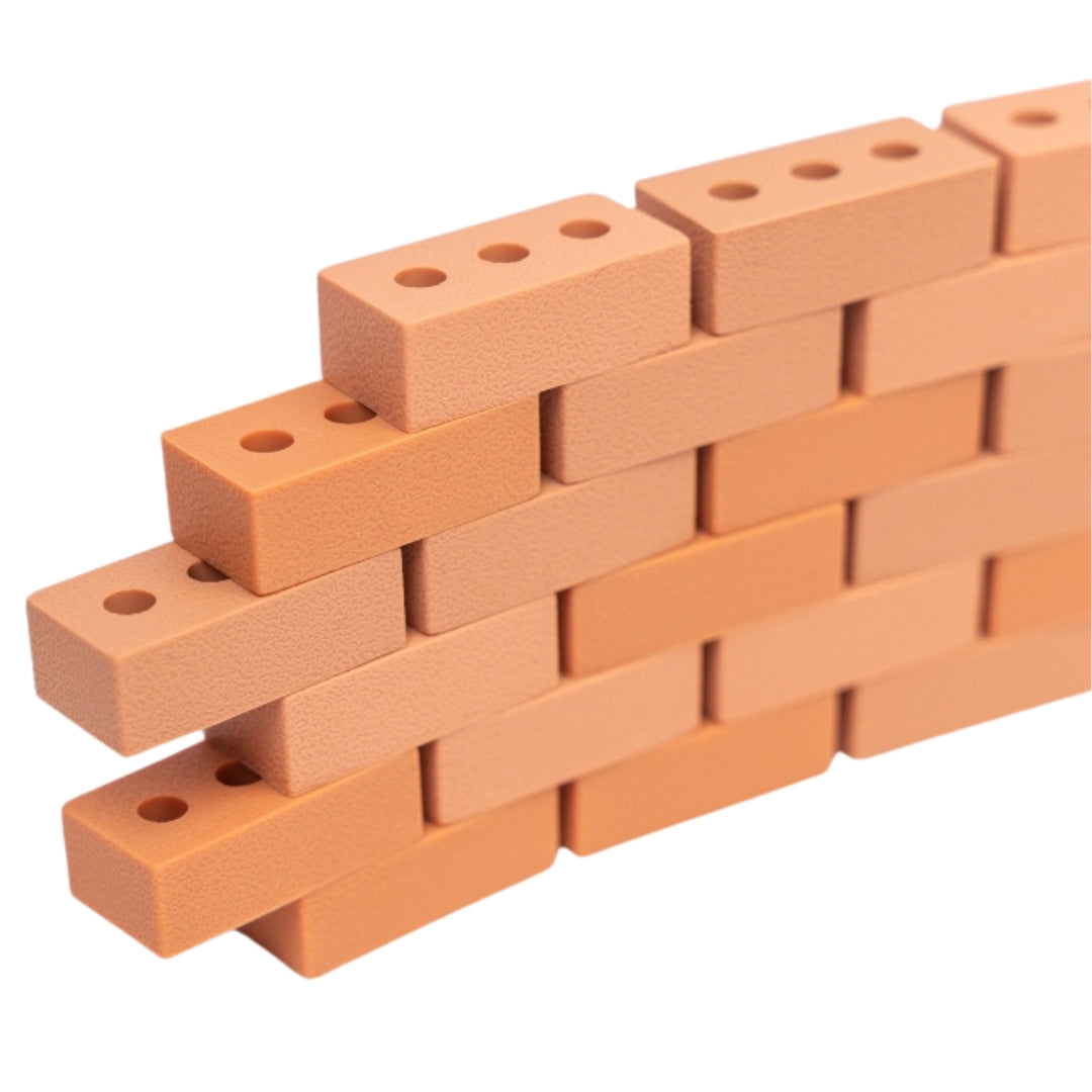 Een schuine muur gebouwd van oranje Inspire My Play mini bricks van siliconen.