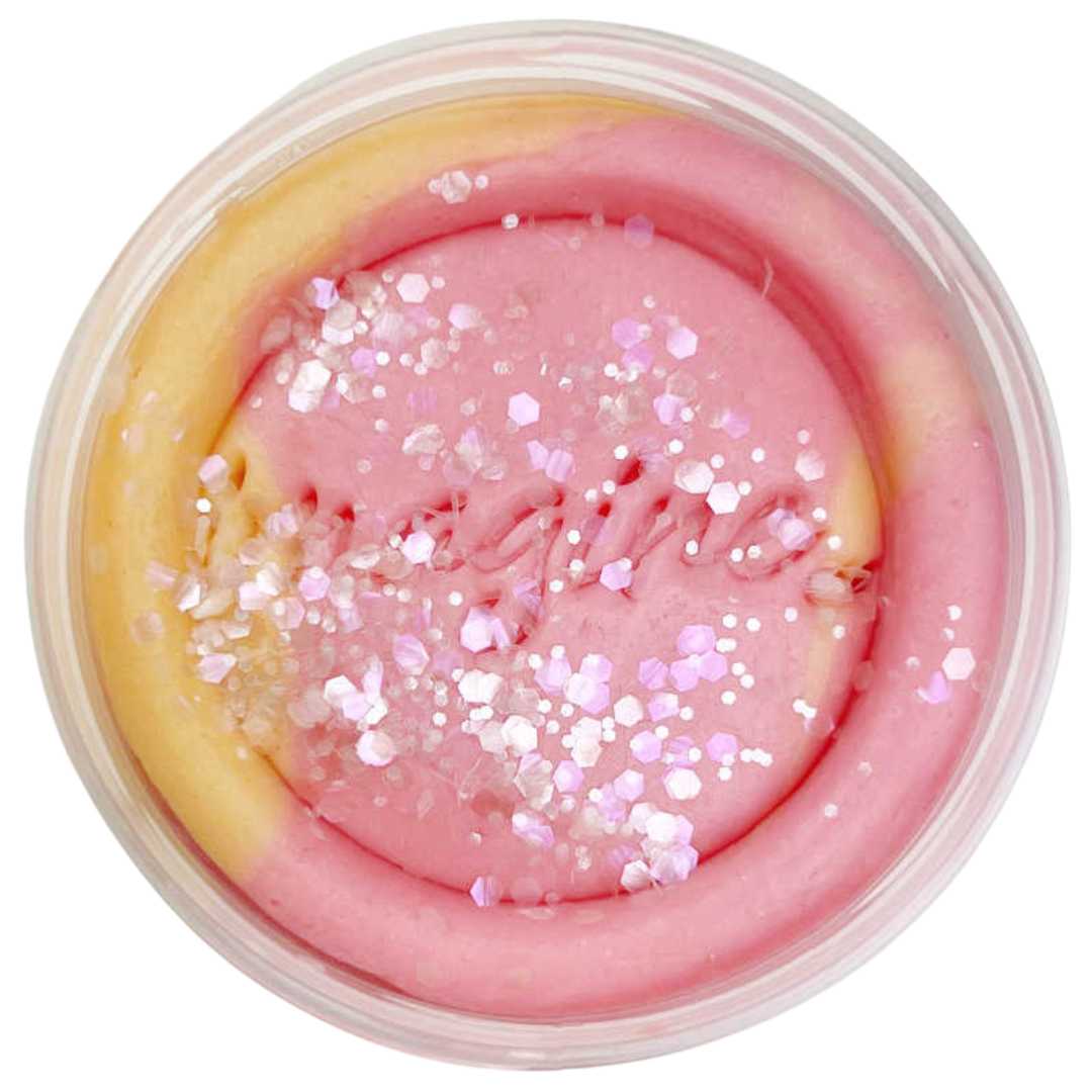 Bovenafbeelding van invitation to imagine speelklei in een potje, met roze en geel klei, glitter en het woord 'imagine'.