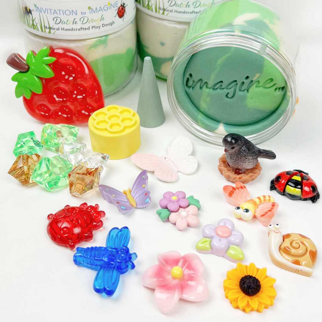 Uitgestalde accessoires van de invitation to imagine speelklei play pot, waaronder insecten, bloemen en een aardbei.