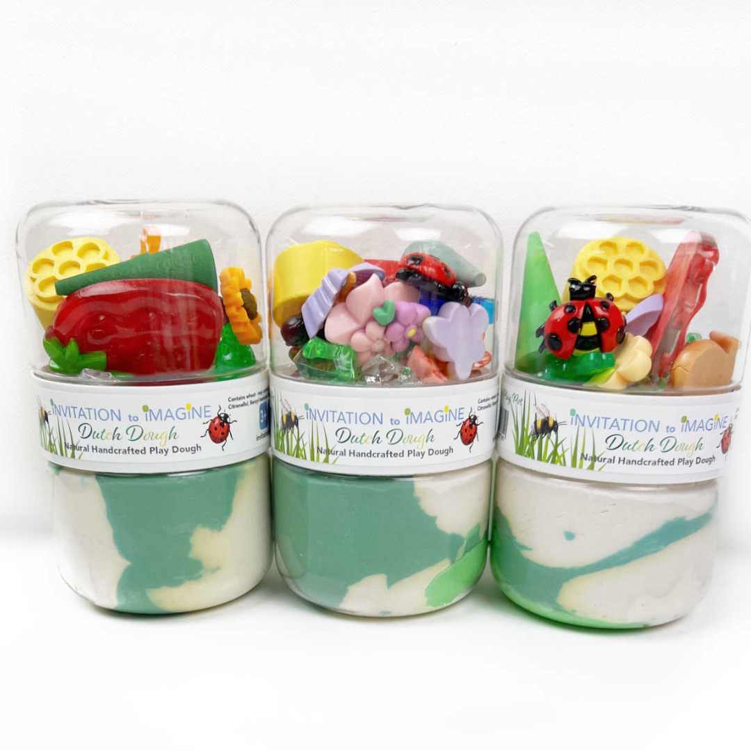 Drie invitation to imagine speelklei play pots met groene en witte klei en tuin-thema accessoires naast elkaar.