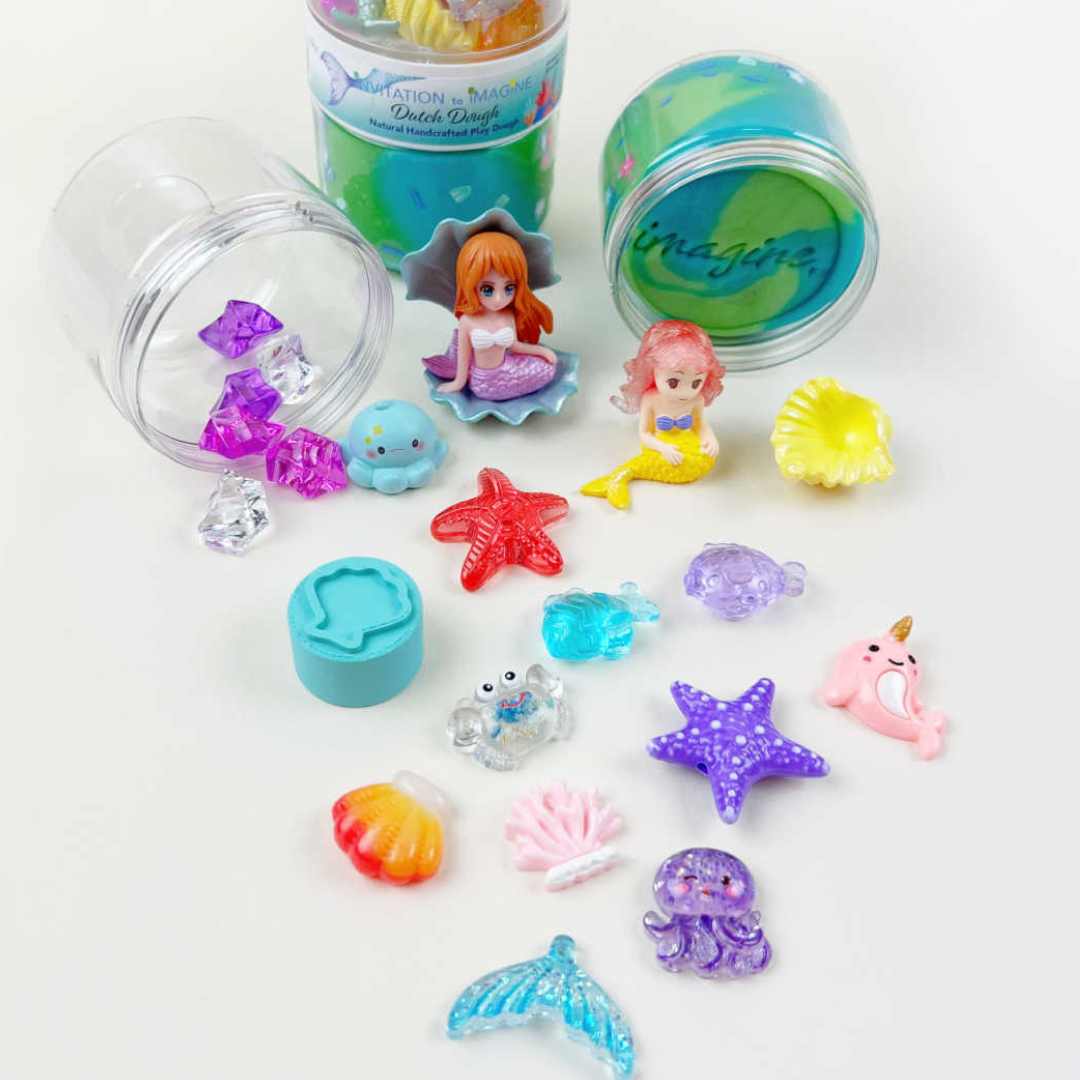 Uitgestalde inhoud van de zeemeermin speelklei set met figuurtjes, schelpen en andere accessoires.