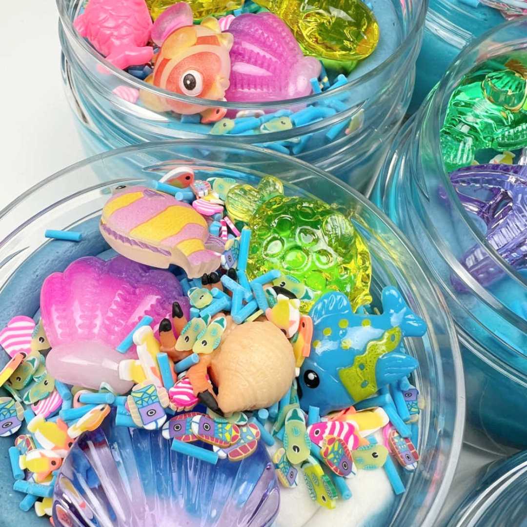 Meerdere potten met blauwe speelklei, plastic zeedieren en kleurrijke sprinkles.