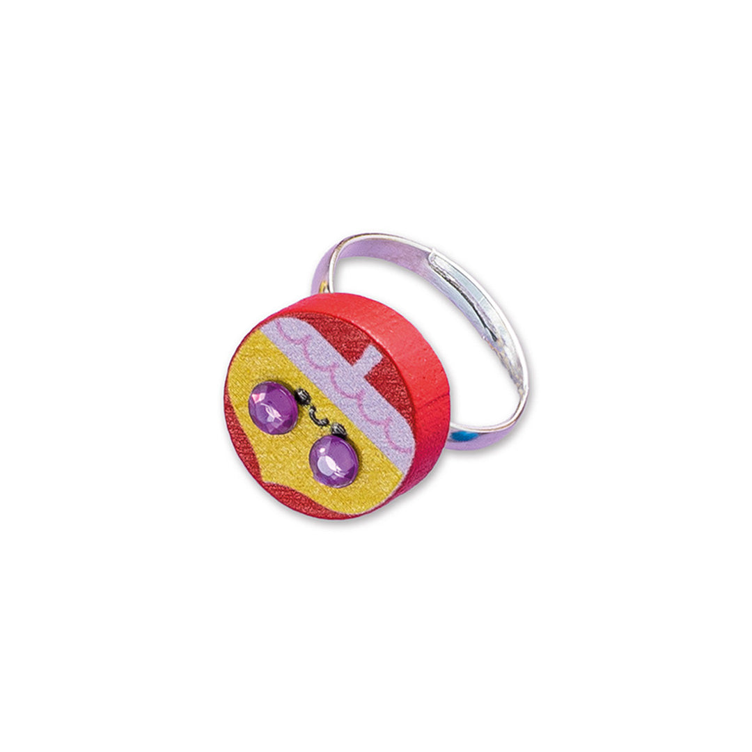 Detail van een Janod Atelier Bijoux ring met een rood houten bedeltje met paarse steentjes.